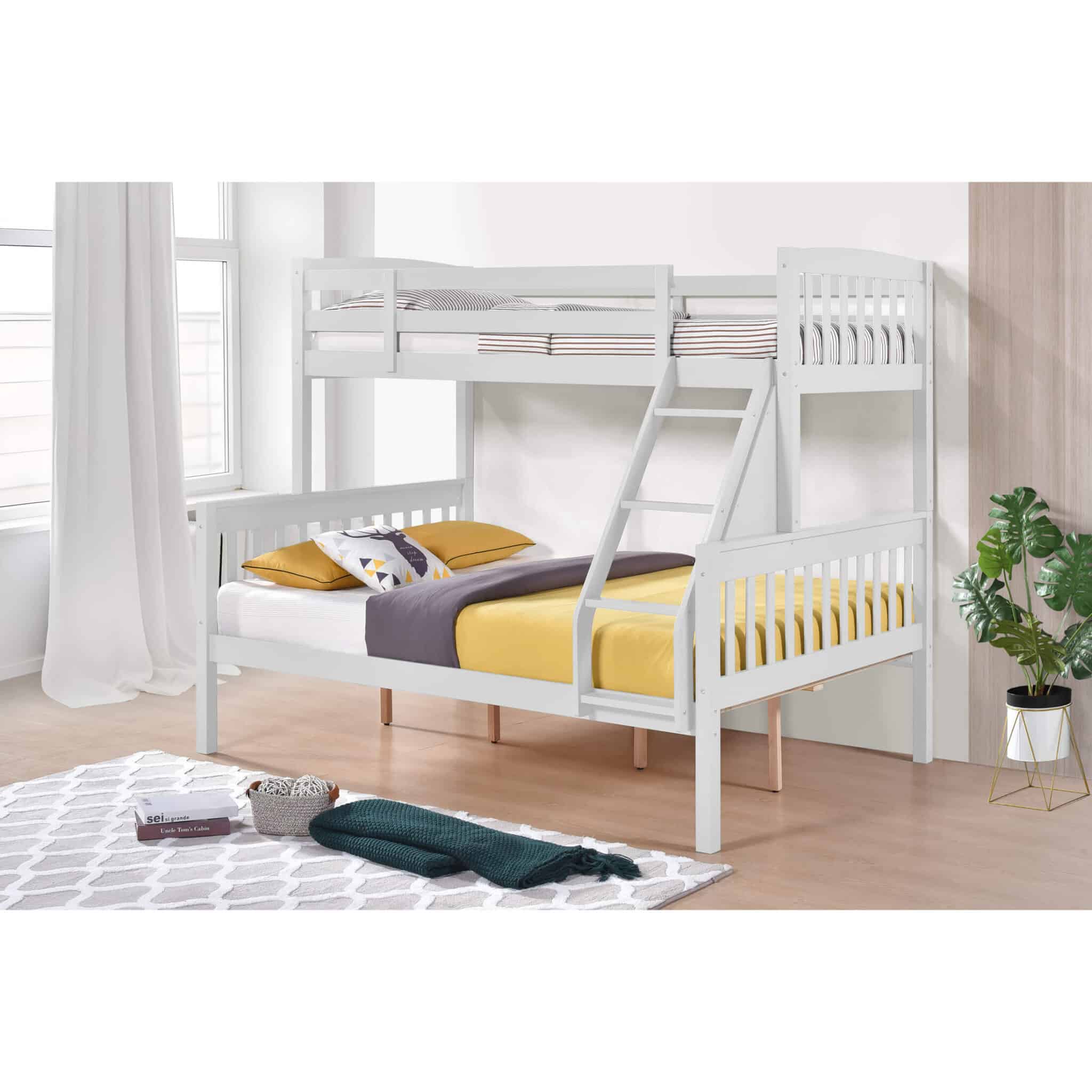 White solid wood triple bunk bed with top single and bottom double bed, yellow and gray bedding, in a bright room with large windows and a potted plant.