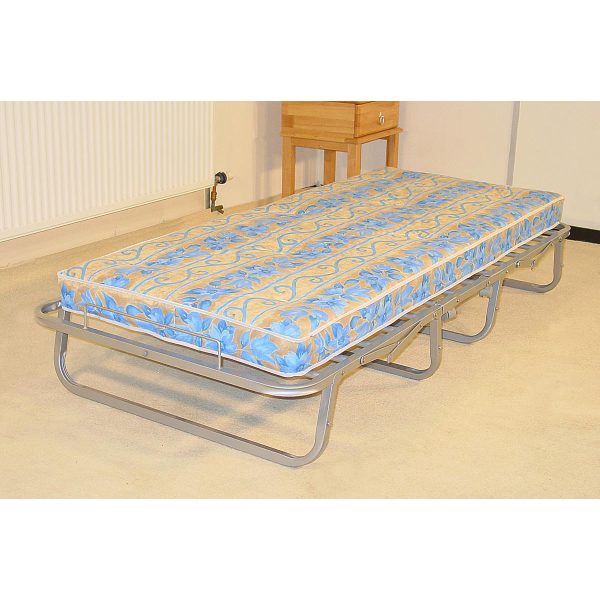 Miami Single Folding Mattress on a silver metal frame with a blue and beige floral pattern, set up in a room with a wooden nightstand and a radiator.